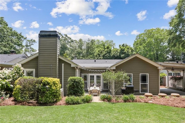 rear view of property featuring french doors, a patio, and a lawn