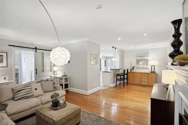 living room with crown molding, wood-type flooring, and a barn door