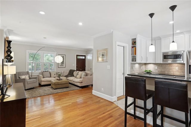 kitchen with a breakfast bar, stainless steel microwave, decorative light fixtures, white cabinetry, and backsplash