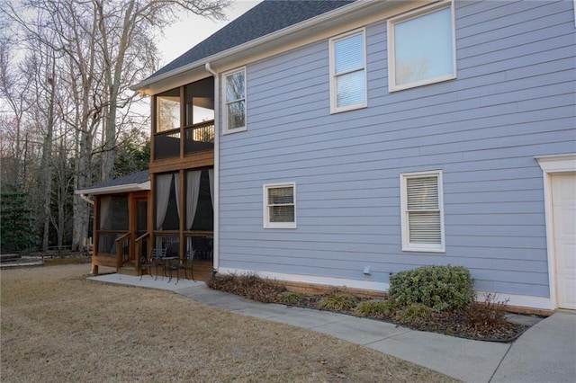 view of home's exterior with a garage, a sunroom, and a shingled roof