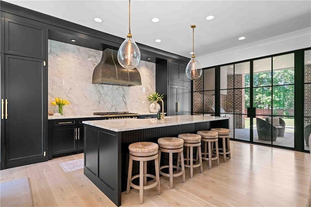 3146 Frontenac Ct NE, Atlanta, GA 30319 - kitchen featuring dark cabinets, premium range hood, light wood-style floors, tasteful backsplash, and light stone counters