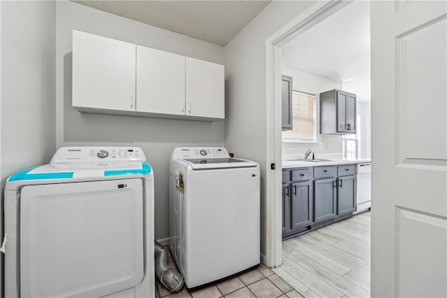 2205 Dresden Grn NW, Kennesaw, GA 30144 - clothes washing area featuring washer and clothes dryer, light wood-style flooring, cabinet space, a textured ceiling, and a sink