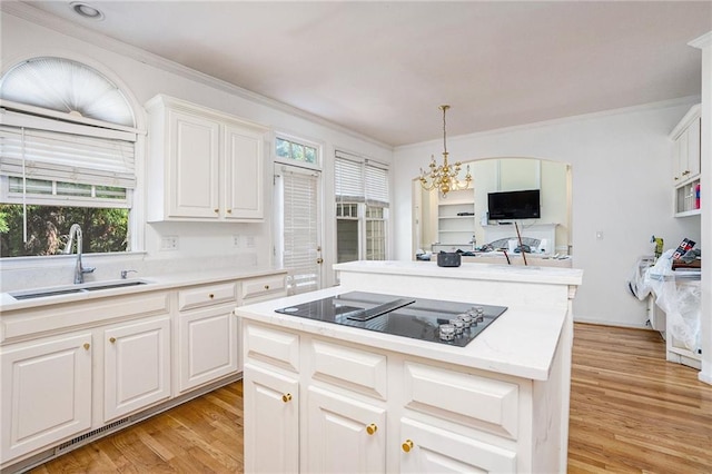 kitchen featuring white cabinetry, sink, a center island, a chandelier, and black electric stovetop