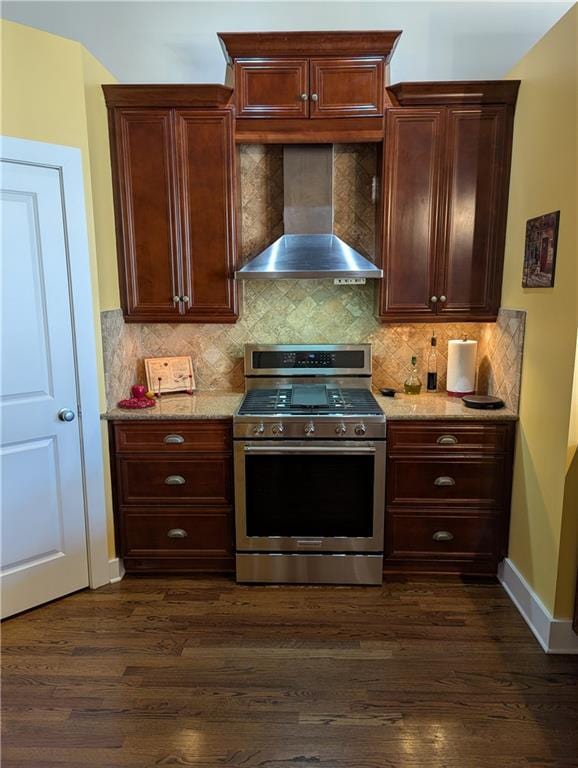 kitchen with light stone counters, dark wood finished floors, decorative backsplash, gas range, and wall chimney exhaust hood