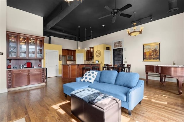 living room with a towering ceiling, light wood-style floors, ceiling fan, and visible vents