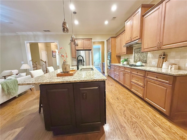 kitchen with a kitchen breakfast bar, visible vents, appliances with stainless steel finishes, a sink, and under cabinet range hood