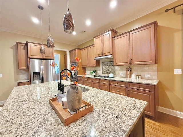 kitchen with a sink, stainless steel appliances, baseboards, decorative backsplash, and ornamental molding