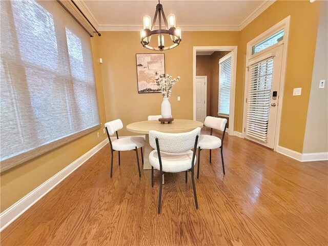 dining space with a chandelier, ornamental molding, light wood-style flooring, and plenty of natural light