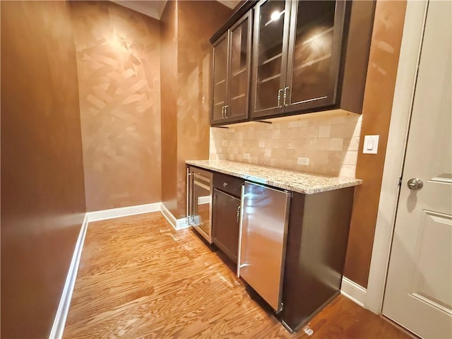 bar with baseboards, tasteful backsplash, fridge, and light wood-style flooring