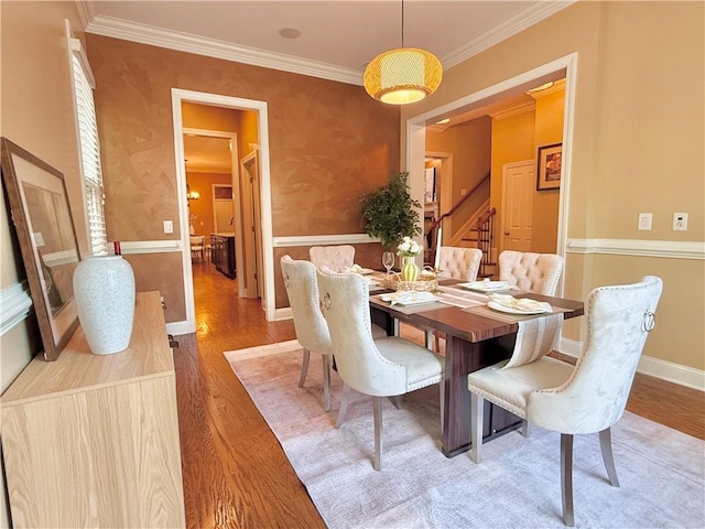 dining room with crown molding, baseboards, light wood finished floors, and stairs