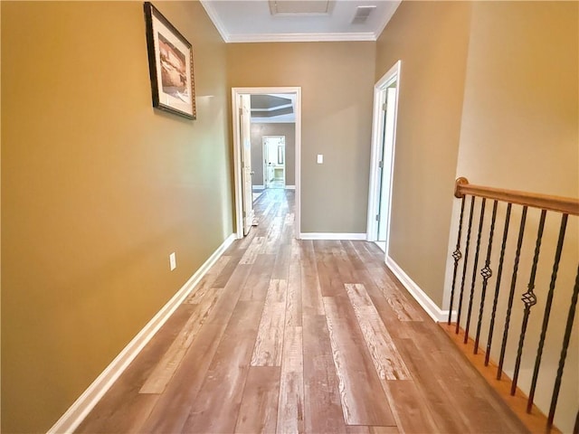 hall with crown molding, baseboards, visible vents, and hardwood / wood-style floors