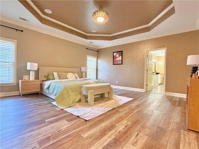 bedroom with light wood-style floors, a raised ceiling, baseboards, and visible vents
