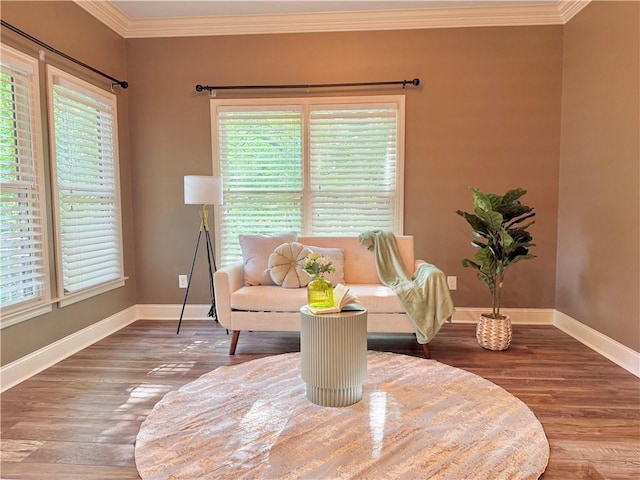 living area with baseboards, ornamental molding, and wood finished floors