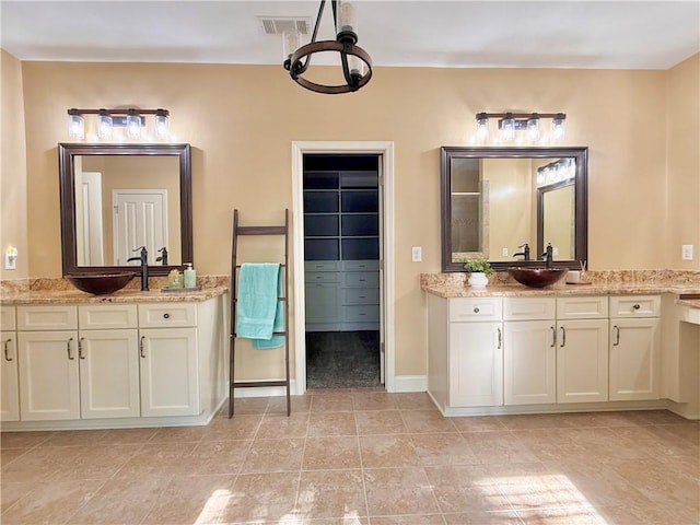 full bathroom with a notable chandelier, two vanities, a sink, and visible vents