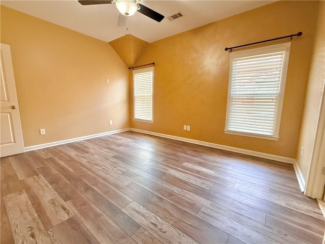 empty room featuring visible vents, wood-type flooring, ceiling fan, and vaulted ceiling