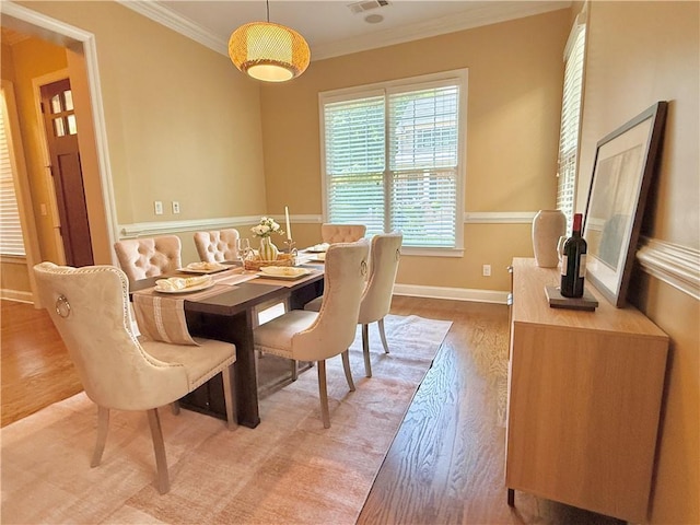 dining space featuring crown molding, baseboards, visible vents, and light wood-type flooring