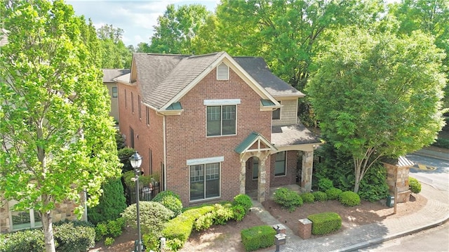 view of front of home featuring roof with shingles and brick siding