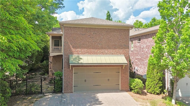 view of front of home with brick siding, an attached garage, fence, and decorative driveway