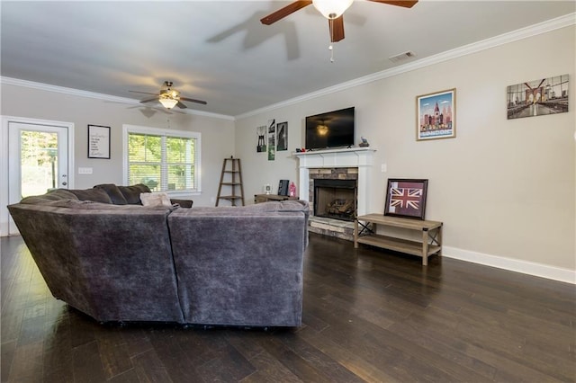 living room featuring ceiling fan, dark hardwood / wood-style floors, crown molding, and a stone fireplace