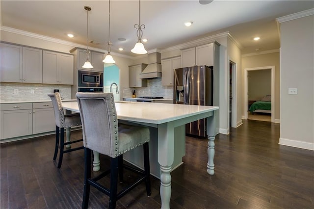 kitchen featuring a kitchen island with sink, appliances with stainless steel finishes, hanging light fixtures, and dark wood-type flooring