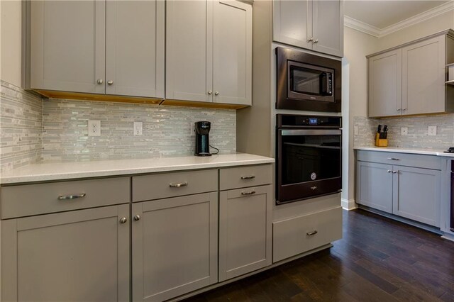 kitchen featuring decorative backsplash, stainless steel appliances, gray cabinetry, dark hardwood / wood-style flooring, and crown molding