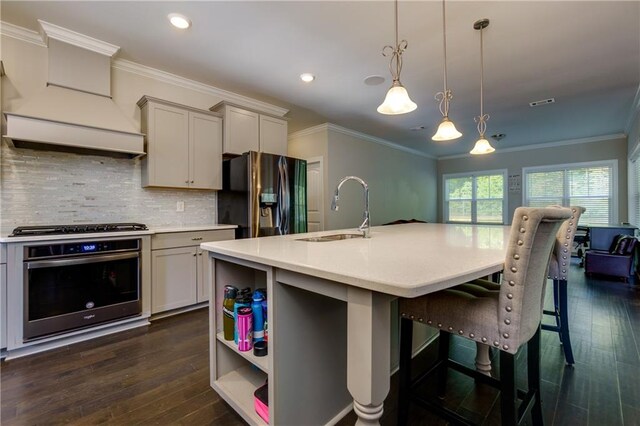 kitchen featuring appliances with stainless steel finishes, pendant lighting, a center island with sink, and dark hardwood / wood-style floors