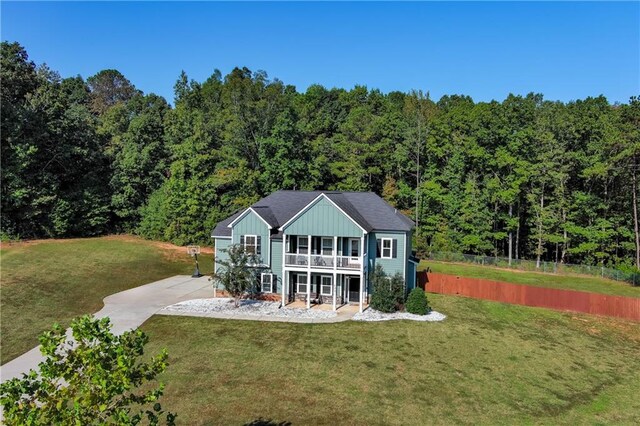 back of house featuring a balcony, a yard, and covered porch