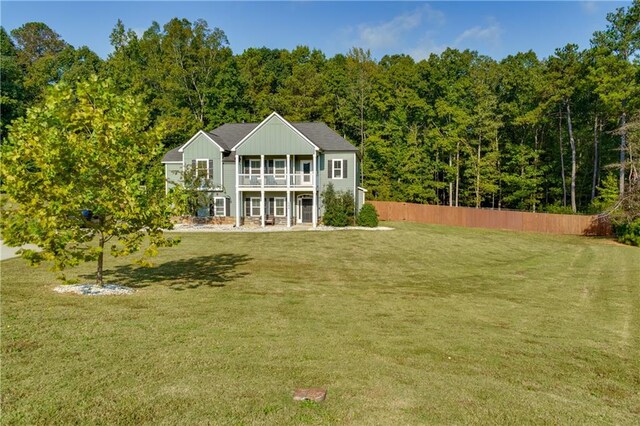 rear view of property featuring a yard, covered porch, and a balcony