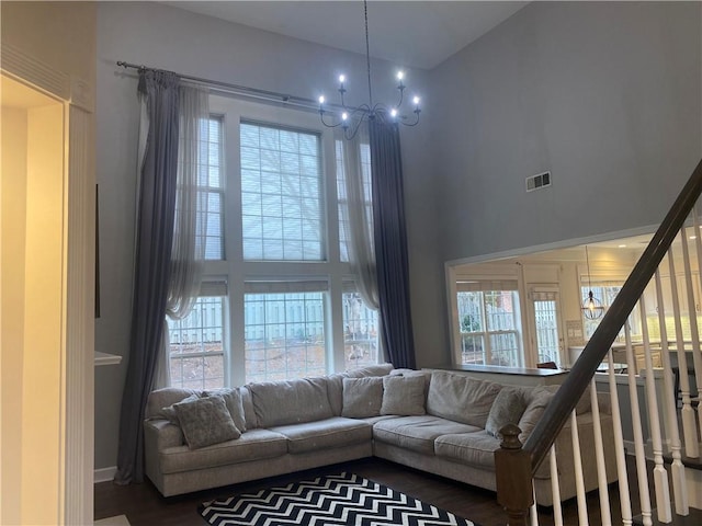 living room with a chandelier, a towering ceiling, and wood-type flooring