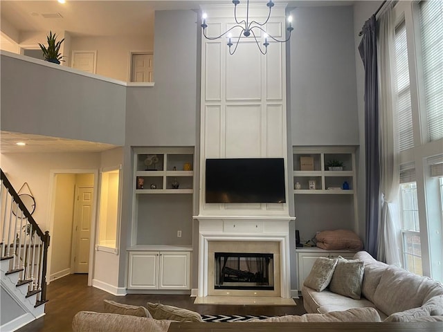 living room with dark hardwood / wood-style flooring, an inviting chandelier, and a towering ceiling