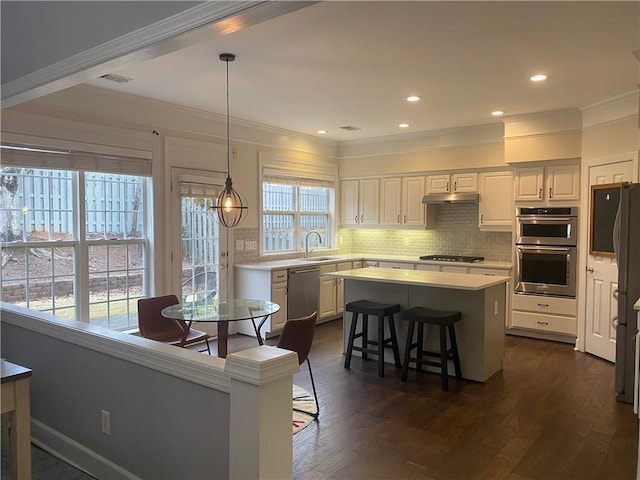 kitchen featuring stainless steel appliances, a center island, hanging light fixtures, white cabinets, and sink