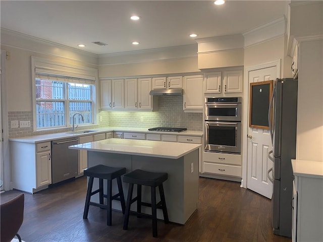 kitchen with stainless steel appliances, white cabinetry, a kitchen island, and sink