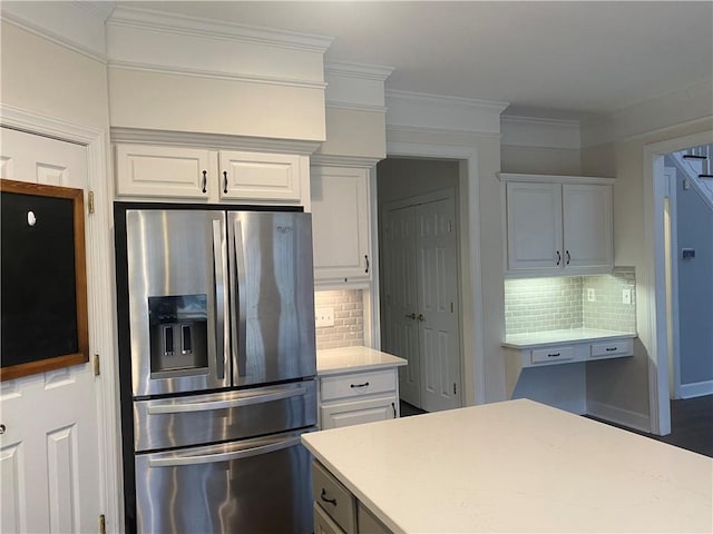 kitchen with tasteful backsplash, stainless steel fridge with ice dispenser, white cabinetry, and ornamental molding