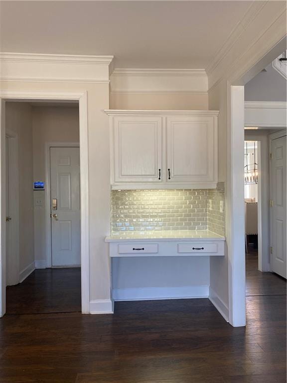 kitchen featuring backsplash, dark hardwood / wood-style floors, crown molding, and white cabinetry