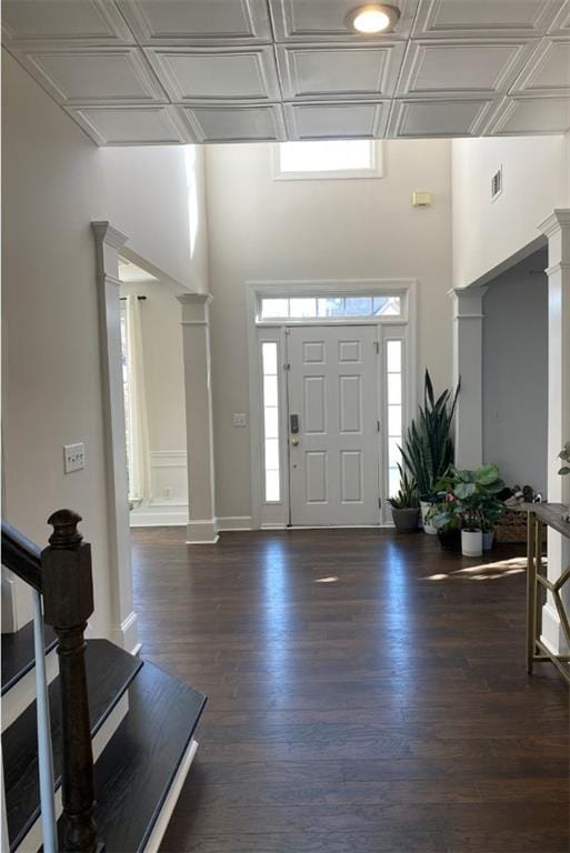 foyer entrance featuring ornate columns and dark hardwood / wood-style flooring