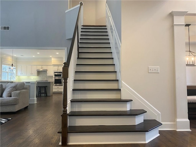 stairs with sink, wood-type flooring, and a notable chandelier