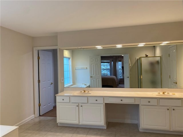 bathroom with a shower with shower door, vanity, and tile patterned flooring