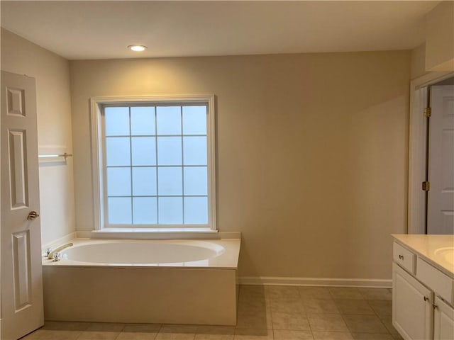 bathroom with a tub to relax in, vanity, and tile patterned floors