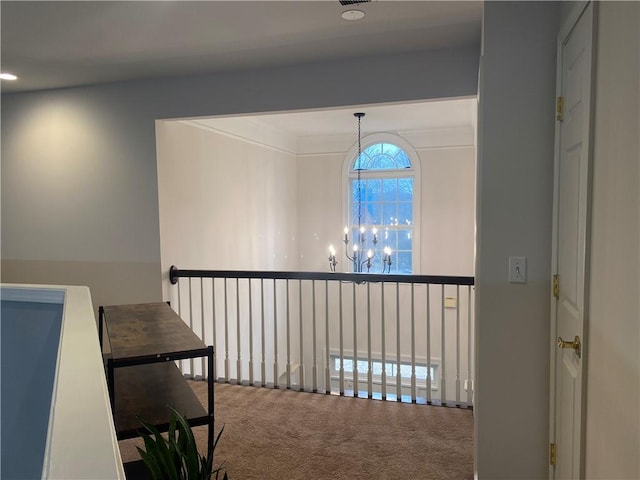 corridor featuring an inviting chandelier and carpet flooring