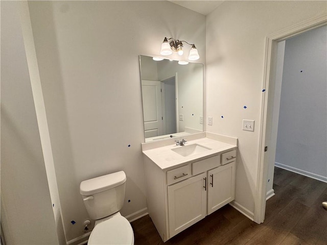 bathroom with vanity, wood finished floors, toilet, and baseboards