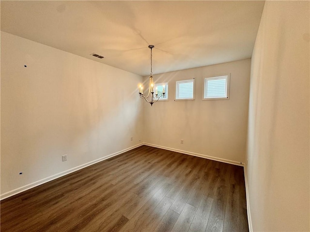 unfurnished room featuring dark wood-style floors, a notable chandelier, visible vents, and baseboards