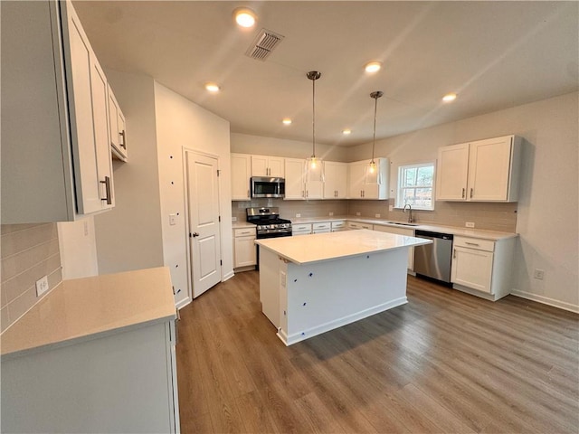 kitchen featuring a kitchen island, visible vents, a sink, appliances with stainless steel finishes, and dark wood finished floors