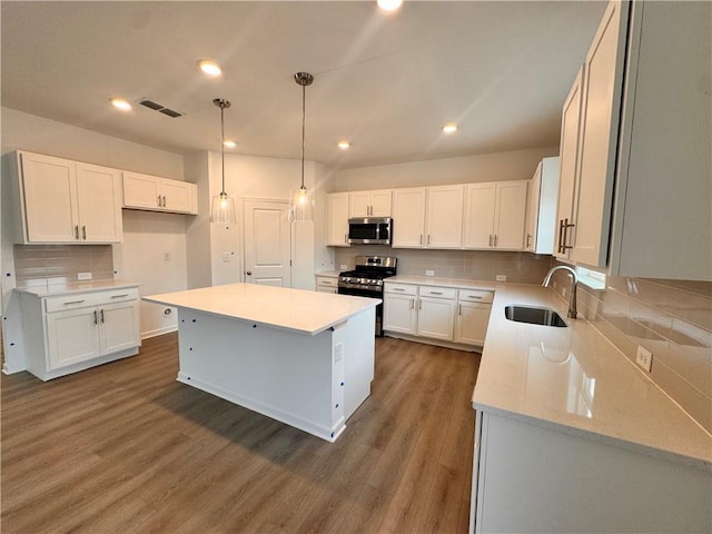 kitchen with visible vents, stainless steel appliances, a sink, and wood finished floors