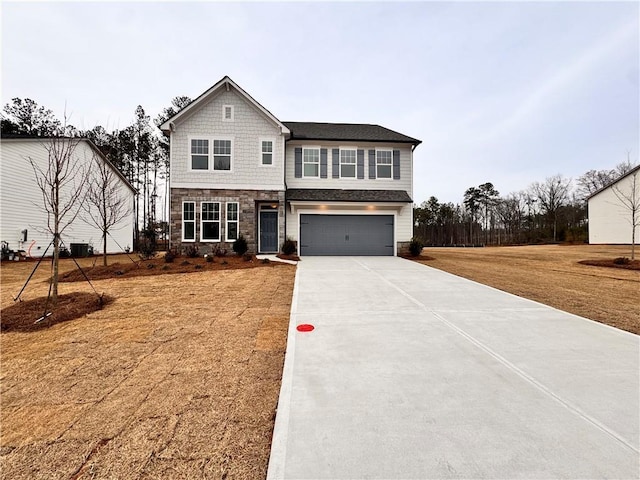 craftsman-style home featuring central AC unit, an attached garage, driveway, stone siding, and a front yard