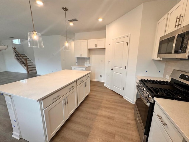 kitchen with tasteful backsplash, visible vents, light wood-style flooring, appliances with stainless steel finishes, and white cabinetry