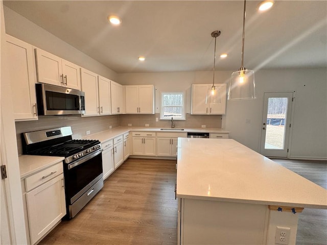 kitchen featuring a kitchen island, stainless steel appliances, backsplash, and light countertops