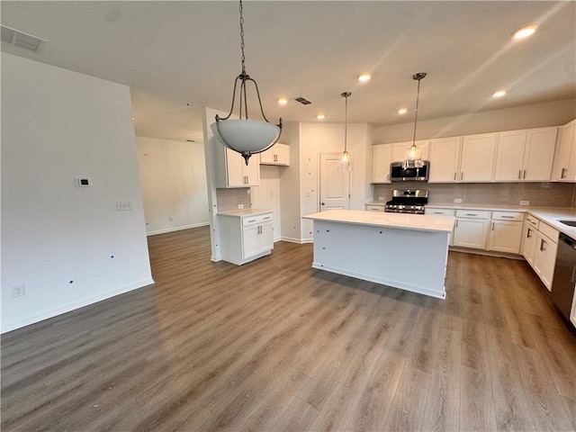 kitchen featuring visible vents, decorative backsplash, appliances with stainless steel finishes, wood finished floors, and white cabinetry