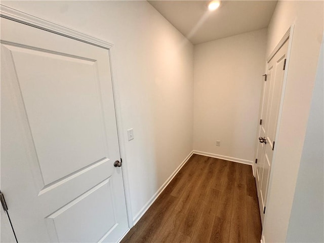 hall featuring dark wood-style flooring and baseboards