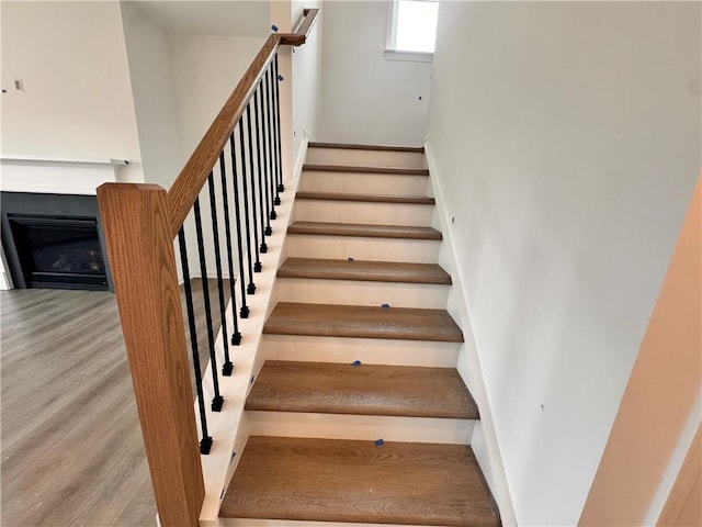 stairway featuring a fireplace and wood finished floors