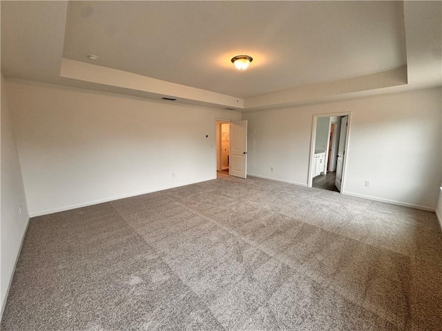 spare room with baseboards, visible vents, a tray ceiling, and carpet flooring